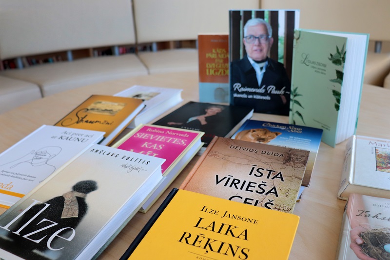 Ilustratīvs attēls - uz galda noliktas guļus grāmatas un fonā tās ir stateniski nedaudz atvērtas