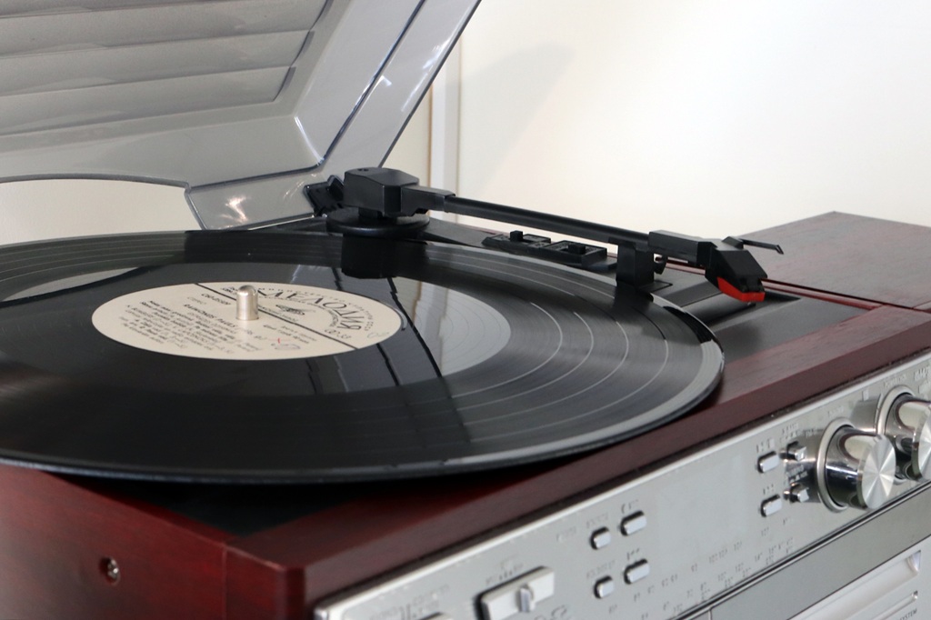 Stilīgs plates atskaņotājs, kas novietots uz koka galda, izceļot tā retro estētiku un funkcionalitāti.