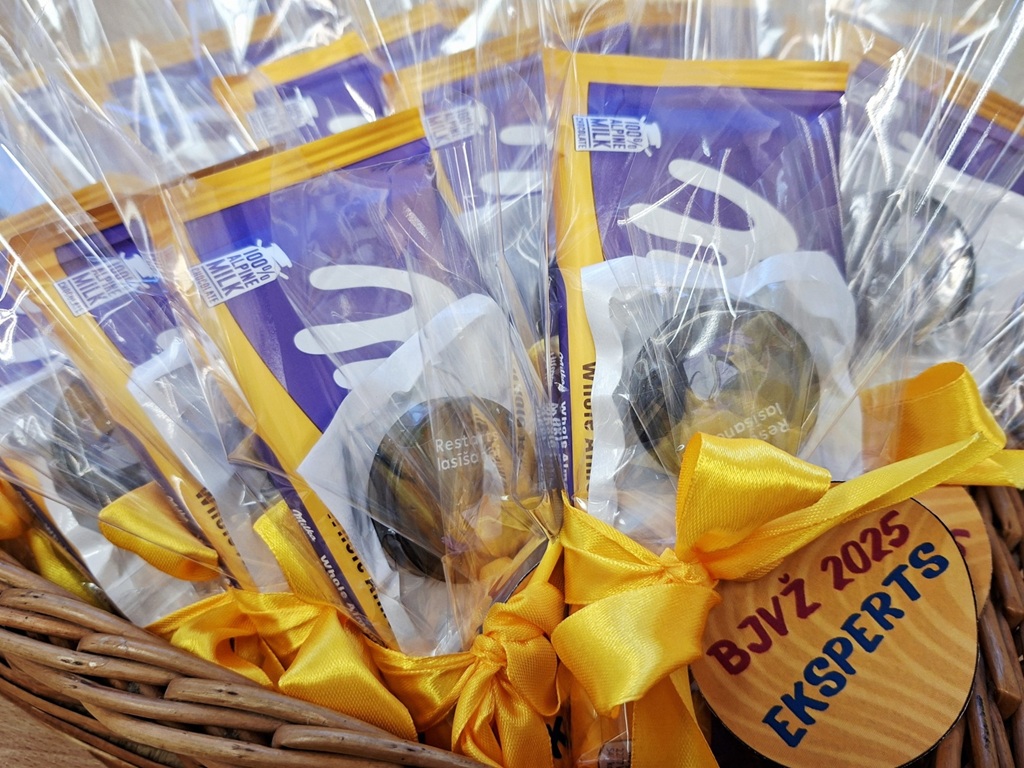 Grozs, kas pildīts caurspīdīgā plēvē iesaiņotiem dāvanu maisiņiem; katrā no tiem ir šokolāde un vēl viens grūti saskatāms priekšmets. Dāvanu maisiņi apsieti ar spilgti dzeltenām lentēm, kas piešķir priecīgu noskaņu.