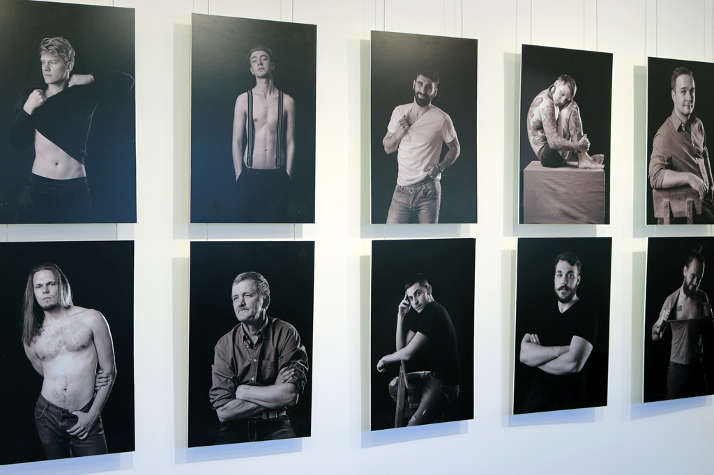 Galerijas sienā uz vienkārša fona ir izvietotas desmit melnbaltas vīriešu portretu fotogrāfijas dažādās pozās, dažas bez krekla, citas ikdienas apģērbā.