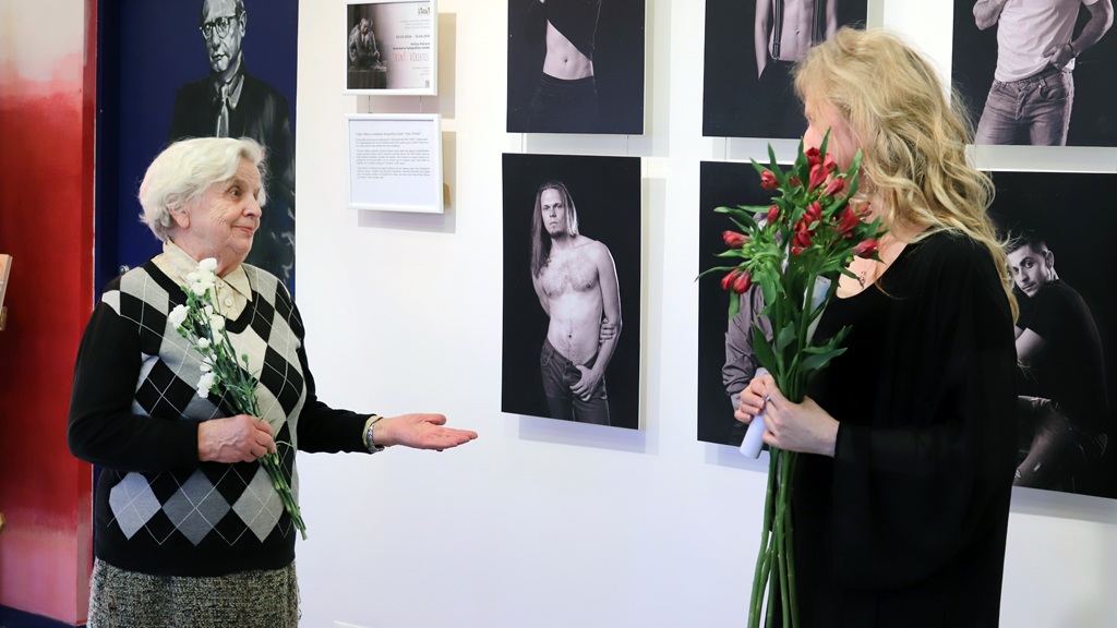 Vecāka gadagājuma sieviete iesaistās sarunā ar jaunāku sievieti, daloties pieredzē un viedokļos.