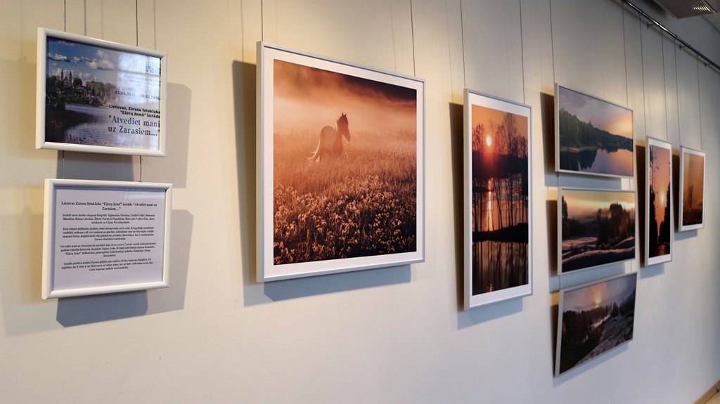 Galerijas sienā ir ierāmētas fotogrāfijas, tostarp miglains zirgs, mierīgas ainavas un saulrieti. Siltie toņi un dabas skaistums rada mieru.