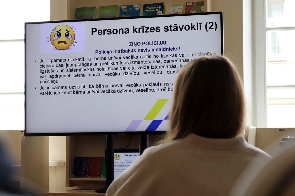 Persona džemperī skata prezentāciju ar slaidu ar nosaukumu "Persona krīzes stāvoklī (2)". Satraukta emocijzīme un teksts izceļ atbalstu krīzes laikā.