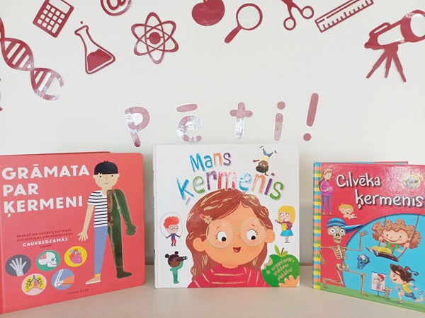 Plauktā vertikāli novietotas trīs krāsainas bērnu grāmatas par cilvēka ķermeni. Fona rotā sarkanas zinātnes tematikas ilustrācijas.