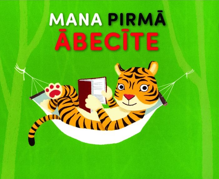 Tīģeris atpūšas šūpuļtīklā, lasot grāmatu uz spilgti zaļa fona. Augšpusē krāsains teksts "Mana Pirmā Ābecīte" piešķir jautru un rotaļīgu noskaņu.
