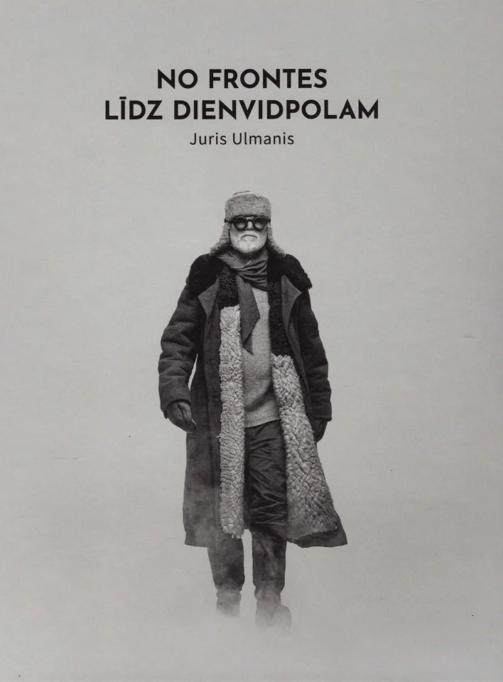 Jura Ulmaņa grāmatas "No frontes līdz Dienvidpolam" vāks. Melnbalta fotogrāfija ar vīrieti biezā ziemas mētelī, cepurē ar ausainēm un brillēm, kurš iet caur sniegu.