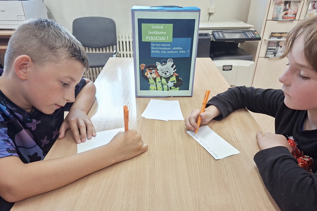 Skolēni piedalās Valsts policijas izglītojošā pasākumā par drošību, gatavojot jautājumus.
