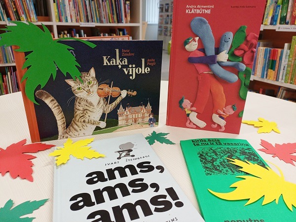 Rudens tematikas bērnu grāmatu izstāde bibliotēkā ar krāsainām papīra lapām