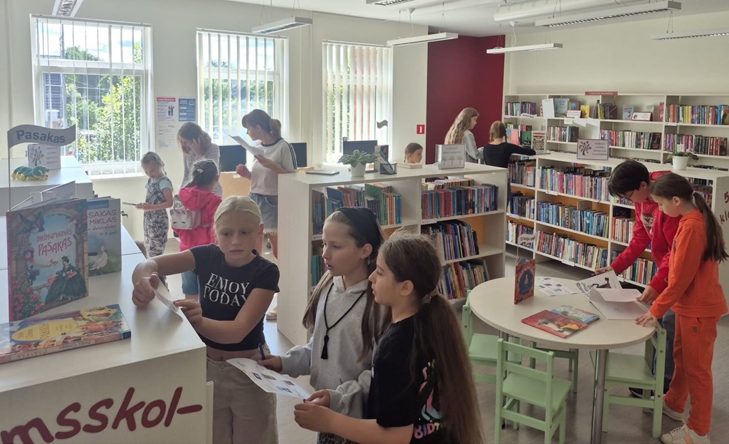Bērni un jaunieši pēta grāmatas un pilda uzdevumus bibliotēkas bērnu nodaļā