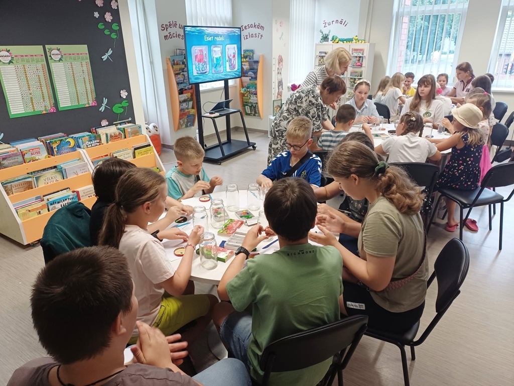 Bērni darbojas ar stikla burkām un plastilīnu radošajā darbnīcā bibliotēkā