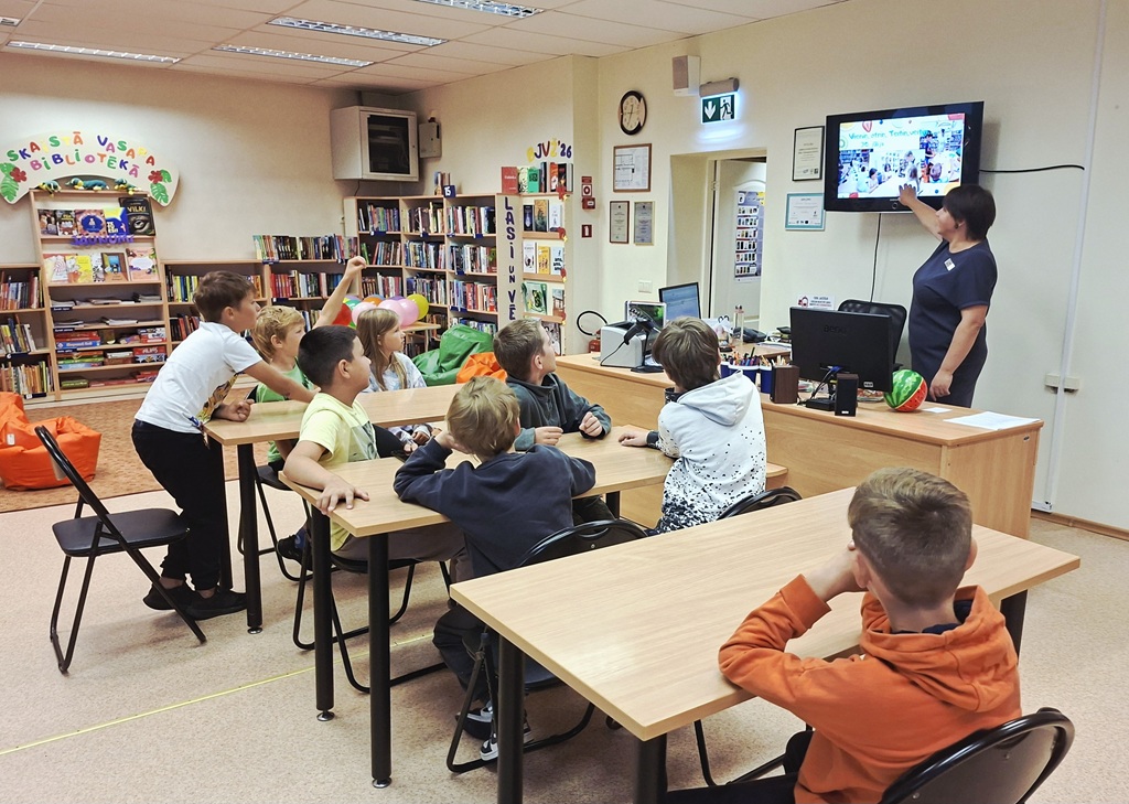 Bibliotēkas darbiniece vada digitālo prezentāciju bērnu izglītojošajā nodarbībā