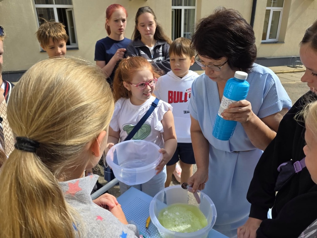Bērni un pasniedzēja vēro zinātniskos eksperimentus un šķidrumu sajaukšanu āra nodarbībā