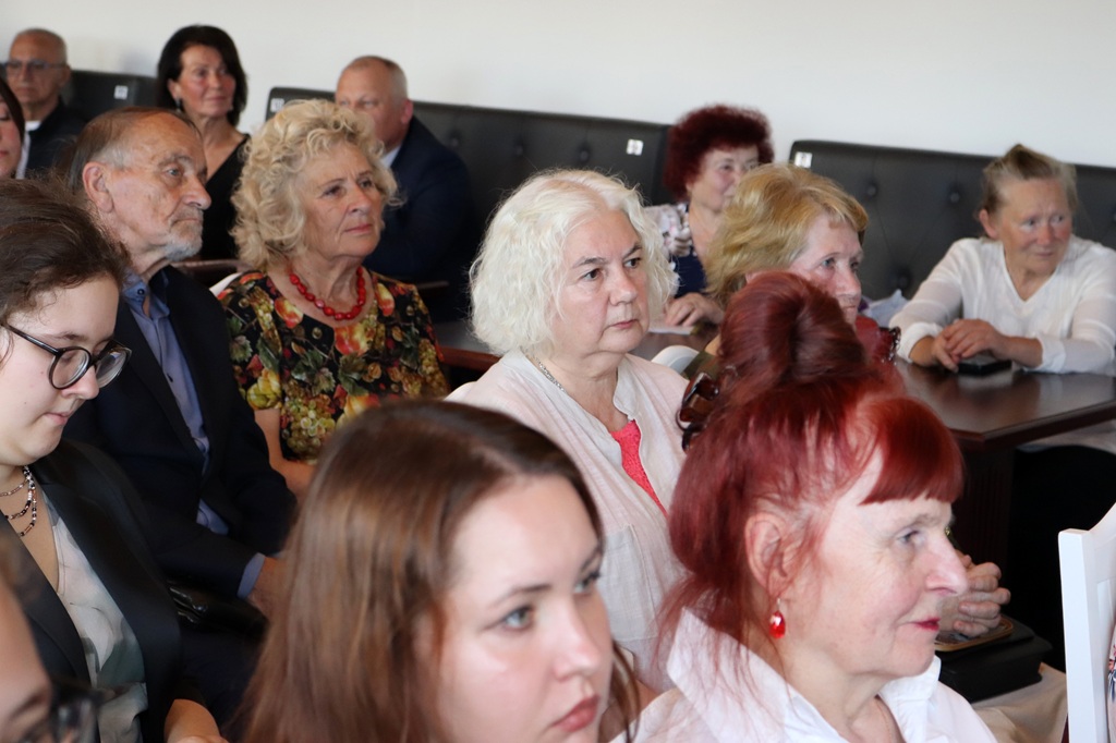 Skatītāji auditorijā uzmanīgi vēro un klausās pasākuma norisi