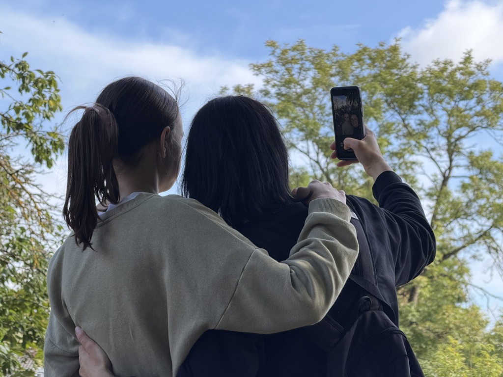 Draudzenes apskaujas un uzņem selfiju brīvā dabā
