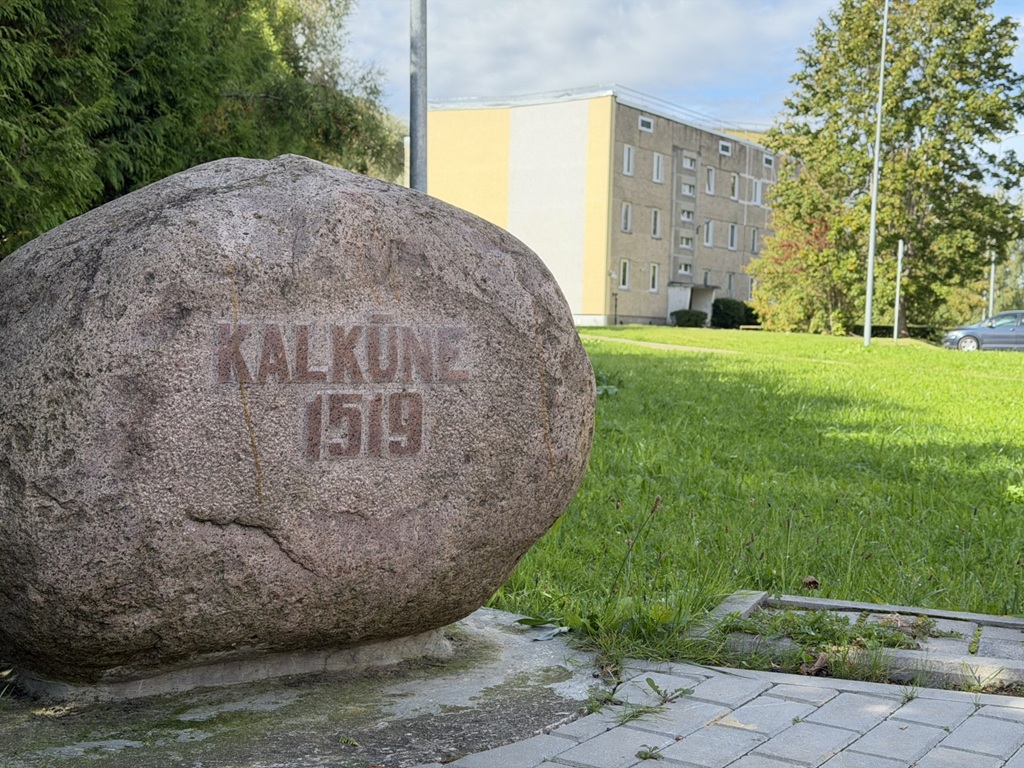 Liels piemiņas akmens ar iegravētu uzrakstu "Kalkūne 1519" zālienā pretī ēkai