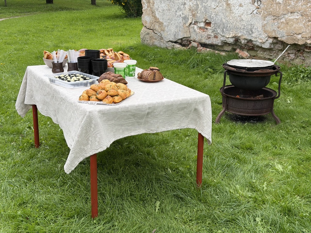 Tradicionāls uzkodas galds āra pasākumā pie senām mūra sienām