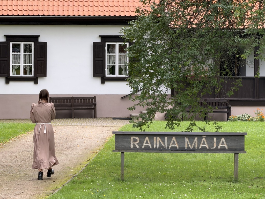 Raina mājas muzeja ēka ar koka zīmi priekšplānā