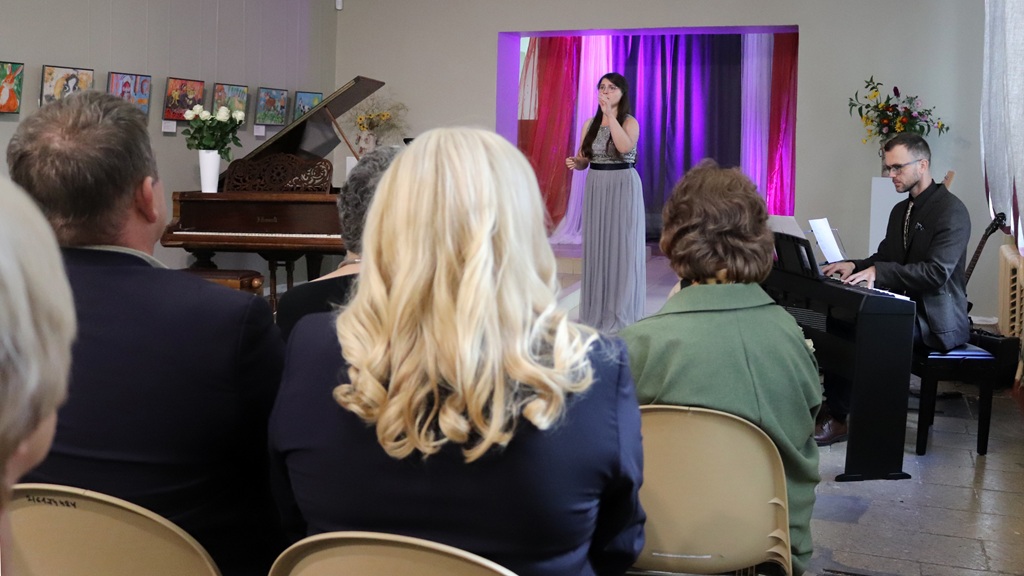 Dziedātāja un pianists uzstājas koncertā skatītāju pilnā zālē