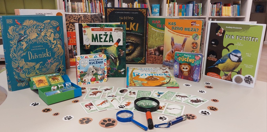 Bibliotēkas grāmatu un spēļu izstāde par dzīvniekiem ar grāmatām, kartītēm un palielināmiem stikliem