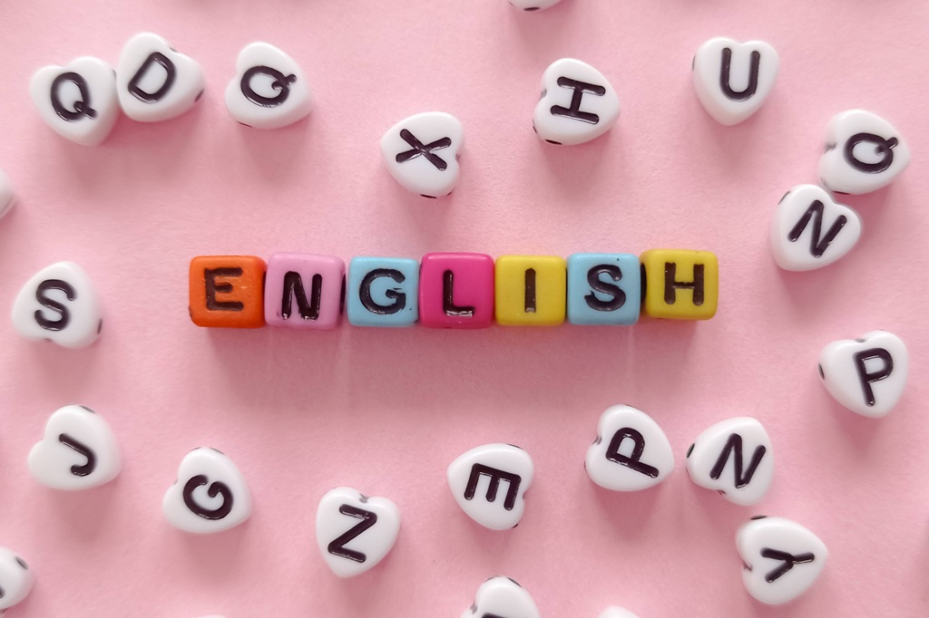 Vārds "ENGLISH", kas salikts no krāsainiem klucīšiem uz rozā fona, ko apņem baltas sirds formas pērlītes ar burtiem