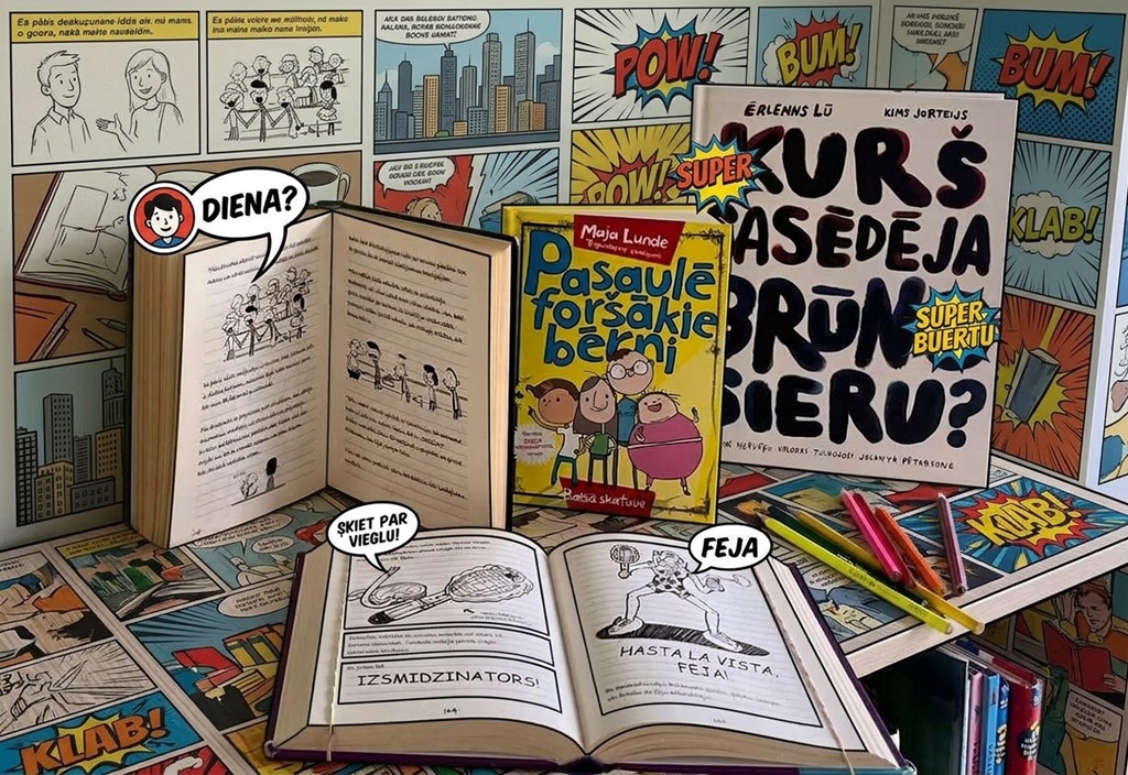 Komiksu grāmatas un atvērti ilustrētie izdevumi, piemēram, "Kurš sasēdēja brūno sieru?, "Pasaulē foršākie bērni", izkārtoti uz grafiska komiksu teksta fona un ar zīmuļiem uz galda.