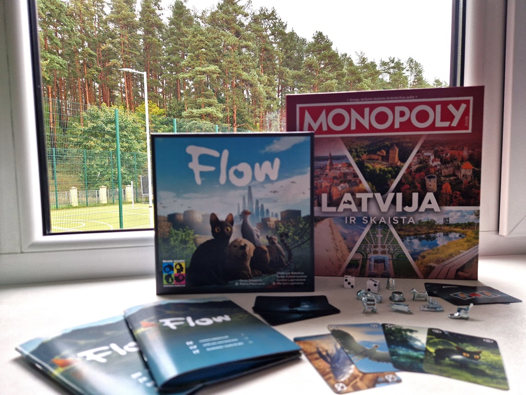 Galda spēles "Flow" un "Monopoly Latvija" izvietotas uz palodzes pretī meža skatam